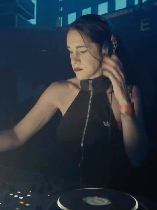 Sole DJing with headphones on, in blue light